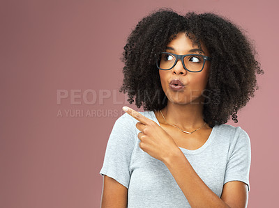 Buy stock photo Studio shot of an attractive young woman pointing against a pink background