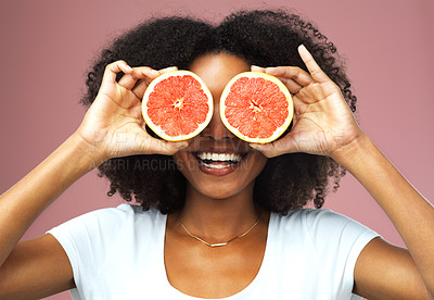 Buy stock photo Studio shot of an attractive young woman covering her eyes with slices of grapefruit against a pink background
