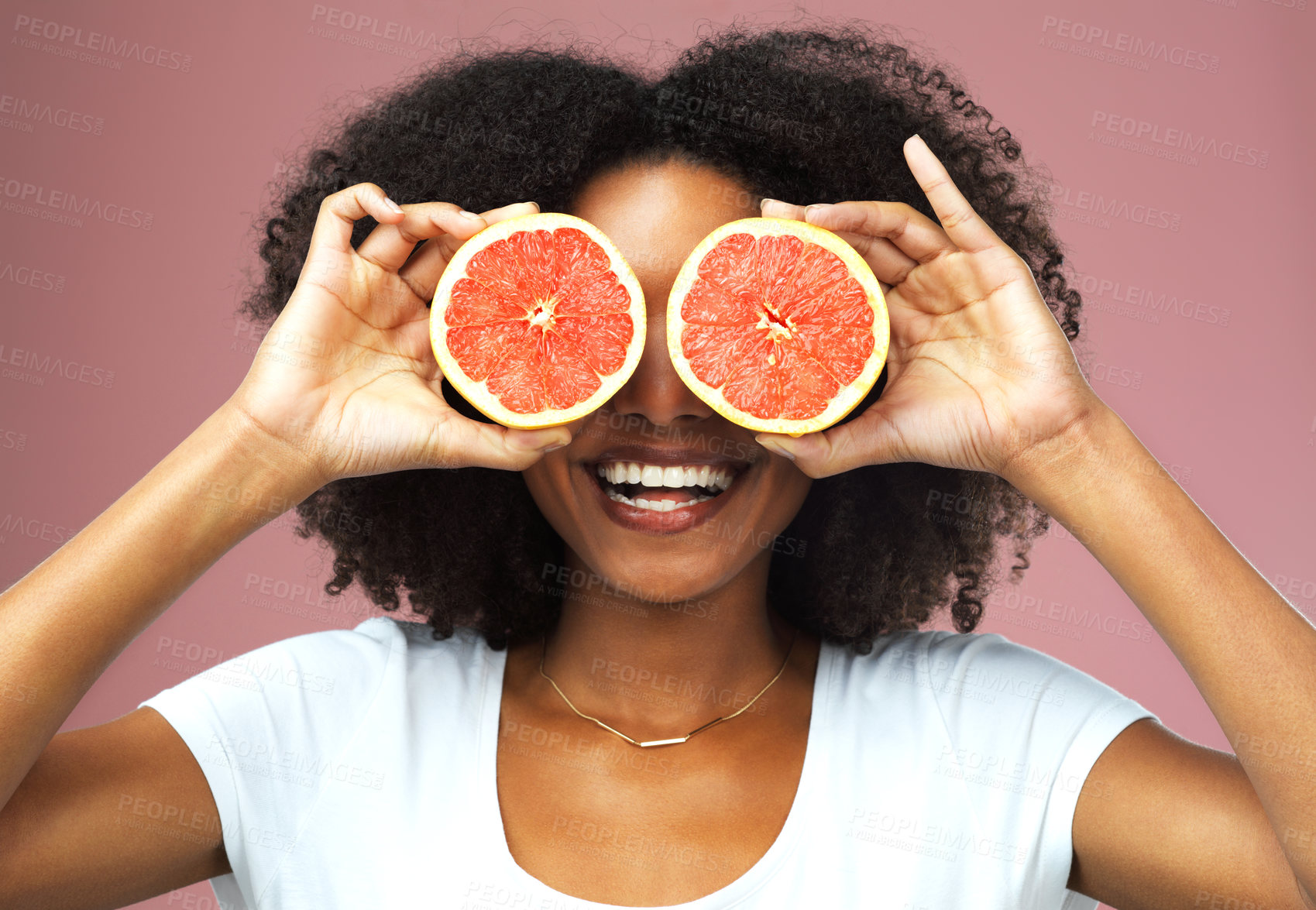 Buy stock photo Studio shot of an attractive young woman covering her eyes with slices of grapefruit against a pink background