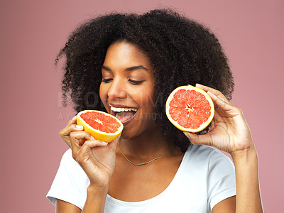 Buy stock photo Grapefruit, happy and black woman eat in studio isolated on a pink background. Natural, fruit and African female model eating food for vegan nutrition, vitamin c or healthy diet, hungry and wellness.