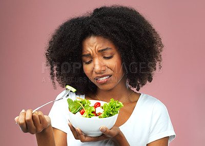 Buy stock photo Unhappy, salad and dislike of black woman in studio eating vegetables for nutrition or vegan diet. Girl, pink background and health for food, detox and wellness benefits for weight loss and disgust