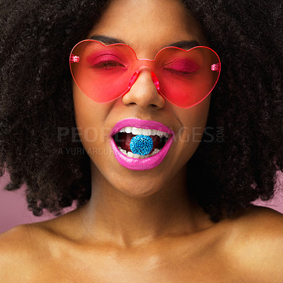 Buy stock photo Studio shot of an attractive young woman biting a piece of candy against a pink background