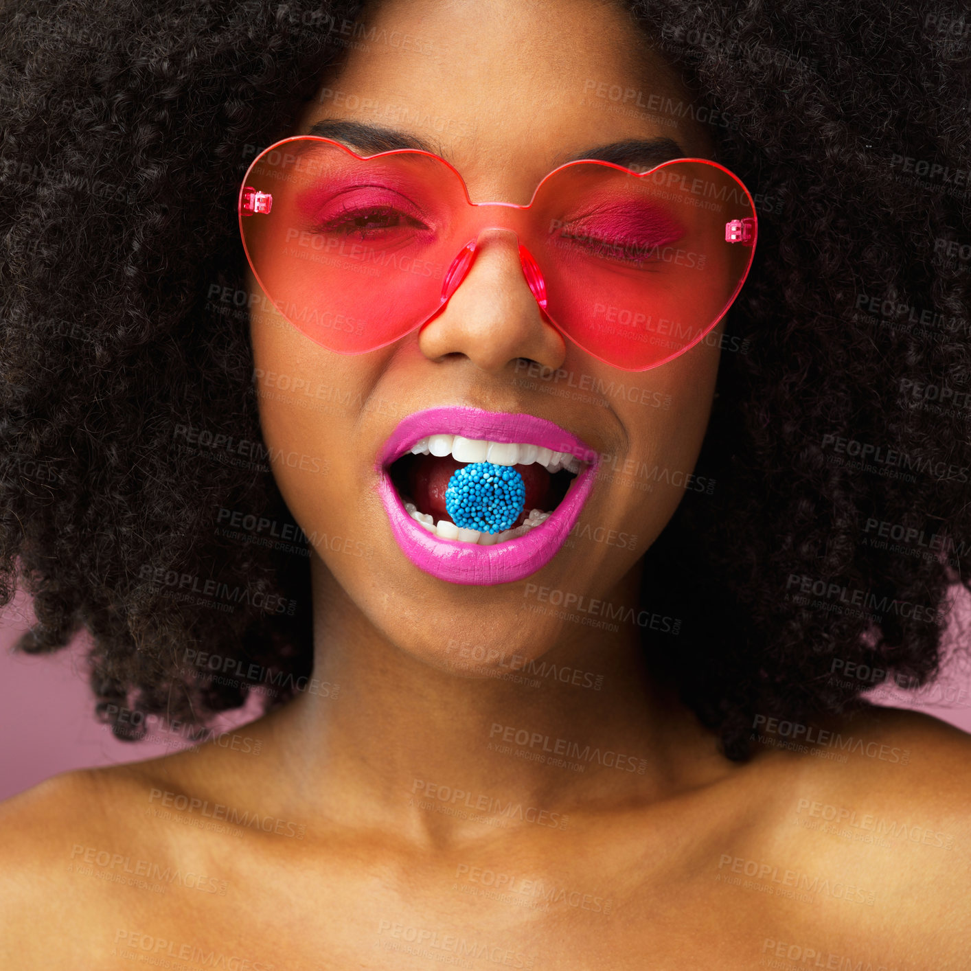 Buy stock photo Studio, portrait and woman with candy in mouth for sweet treat, lipstick and colorful style. Heart, sunglasses and female person with sugar on pink background for funky accessory, confidence or snack