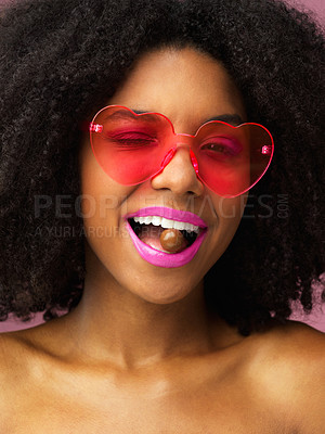 Buy stock photo Studio shot of an attractive young woman biting a chocolate against a pink background