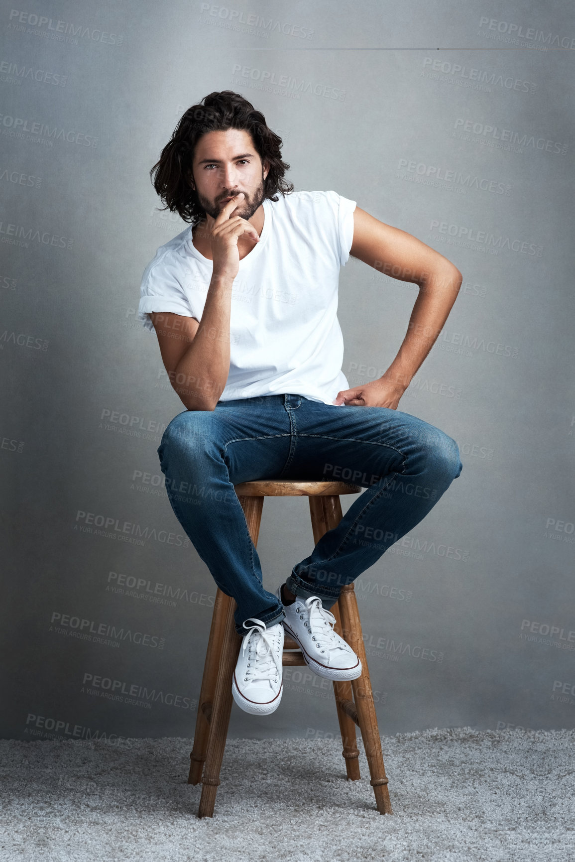 Buy stock photo Casual, fashion, and portrait of man on chair with confidence, designer clothes and thinking in studio. Jeans, pride and cool male model on stool with creative style, inspiration and grey background