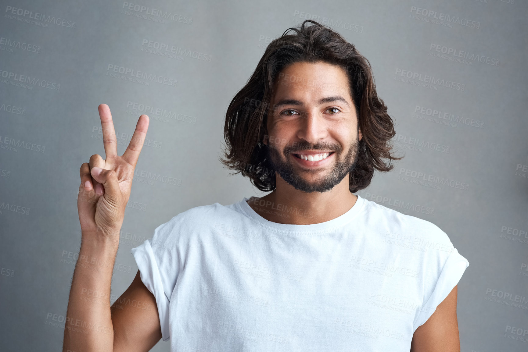 Buy stock photo Studio portrait of a young man showing a peace gesture against a grey background
