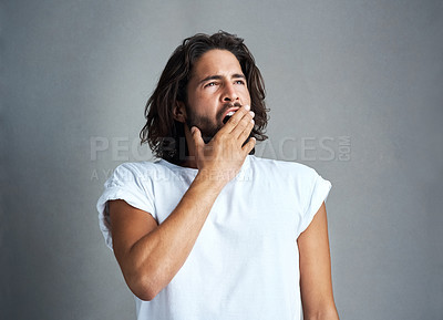 Buy stock photo Studio shot of a handsome young man yawning against a grey background