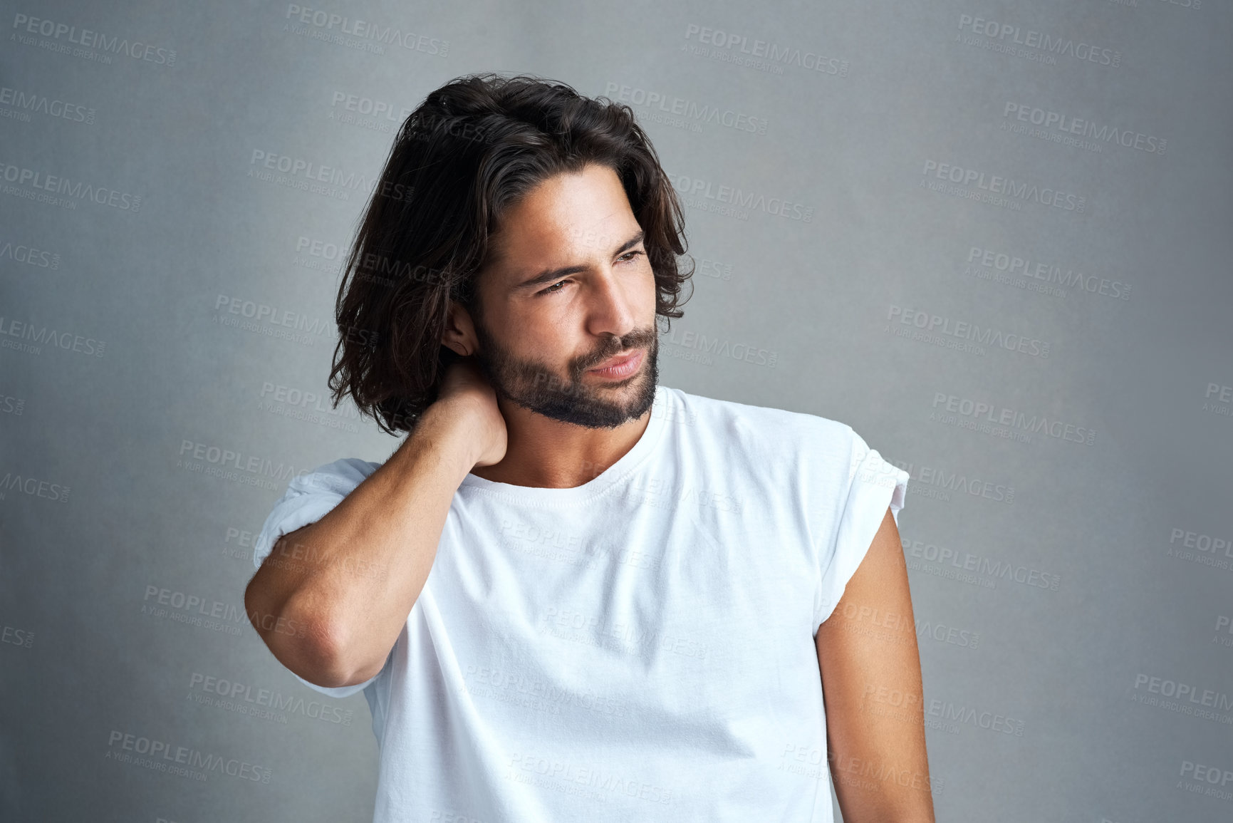 Buy stock photo Studio shot of a handsome young man experiencing neck ache against a grey background