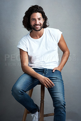 Buy stock photo Fashion, smile and portrait of man in studio on a stool with casual, cool and stylish outfit. Happy, handsome and confident young male model from Mexico with trendy style on chair by gray background.
