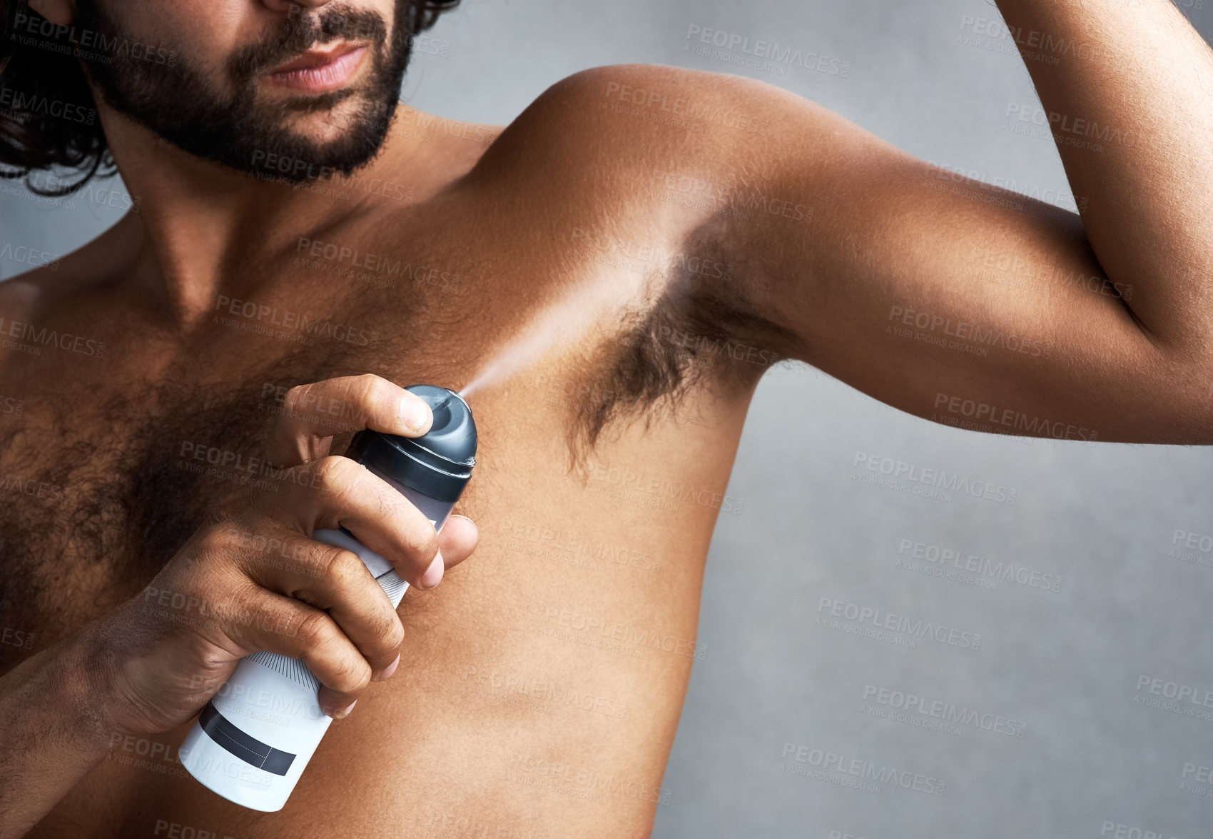 Buy stock photo Studio shot of a handsome young man applying deodorant against a grey background