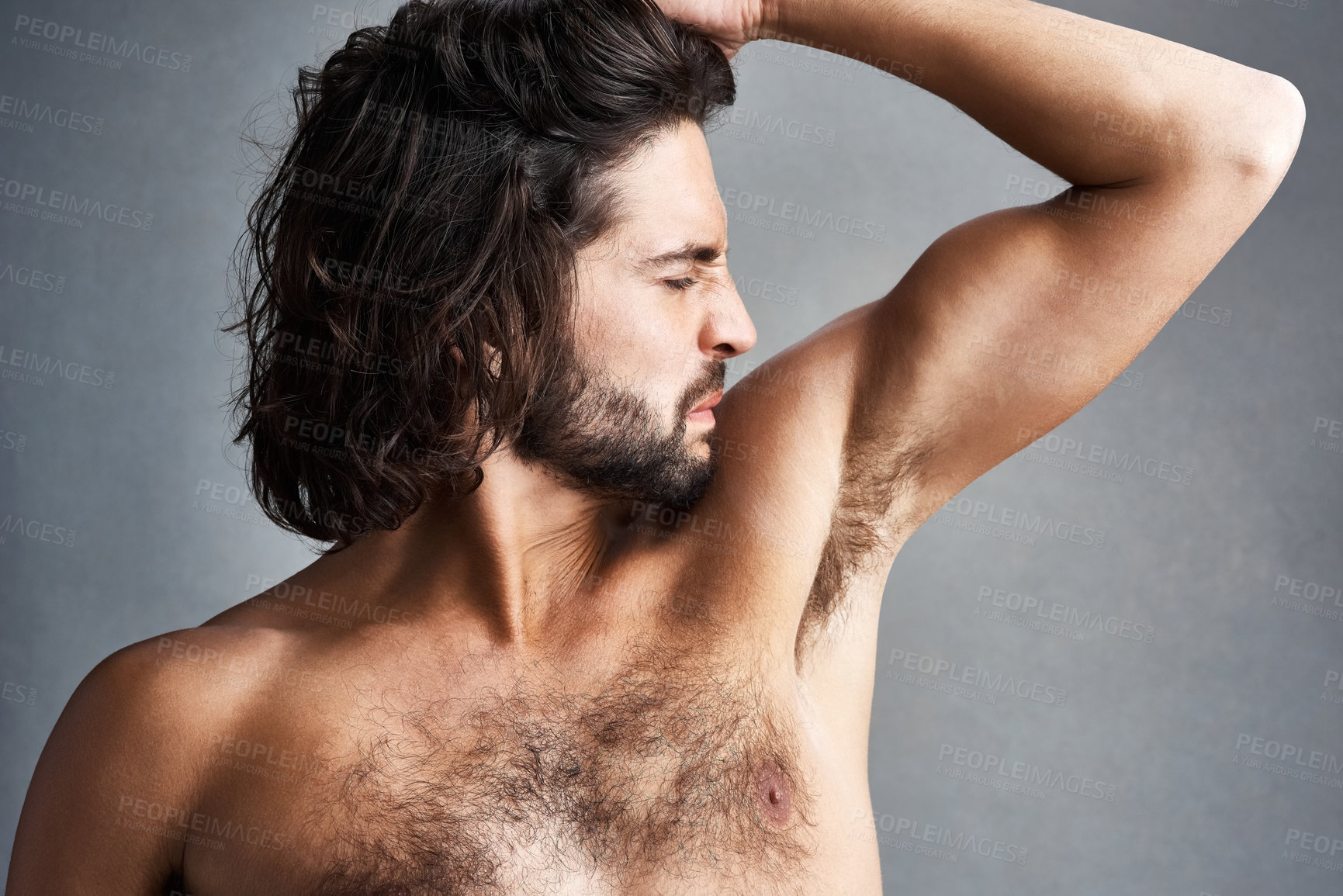 Buy stock photo Studio shot of a young man smelling his armpits against a grey background