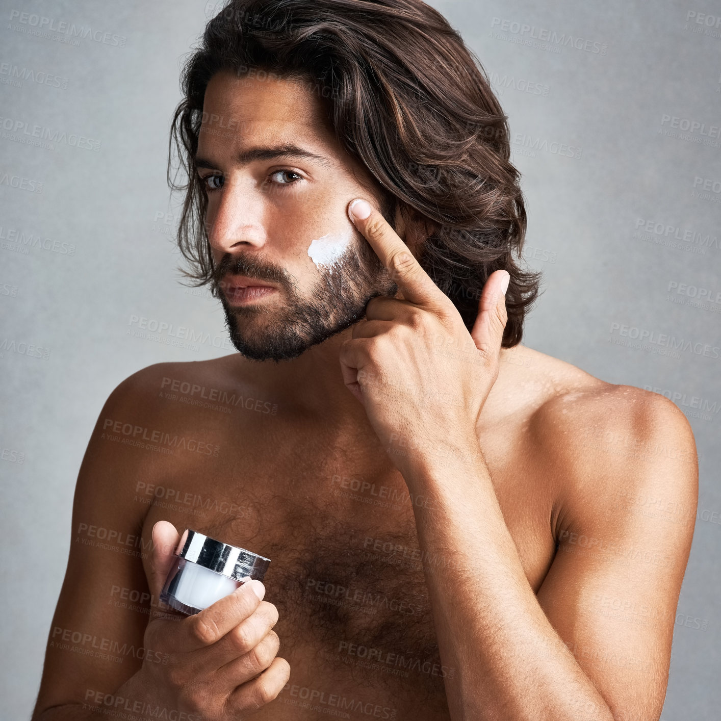 Buy stock photo Portrait, skincare or cream with a shirtless man in studio on a gray background for his grooming routine. Beauty, facial and and the body of a handsome young person with antiaging lotion for his skin