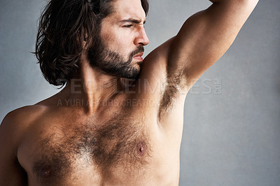 Buy stock photo Studio shot of a young man smelling his armpits against a grey background