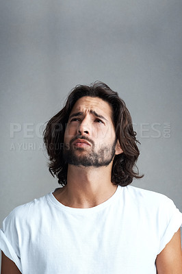 Buy stock photo Studio shot of a handsome young man looking worried against a grey background