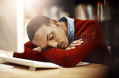 Buy stock photo Shot of a university student sleeping while working on a computer in the library on campus