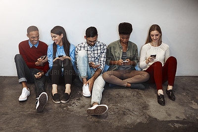Buy stock photo Shot of a group of university students using their cellphones on campus