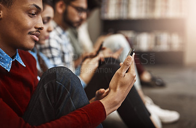 Buy stock photo Shot of a group of university students using their cellphones on campus