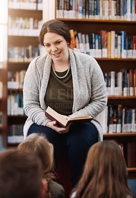 Buy stock photo Cropped shot of an elementary school teacher reading to her kids in the library