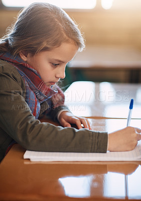 Buy stock photo Cropped shot of an elementary school girl doing her school work in the classroom