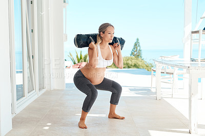 Buy stock photo Shot of a pregnant woman working out with a sand bag on the patio at home