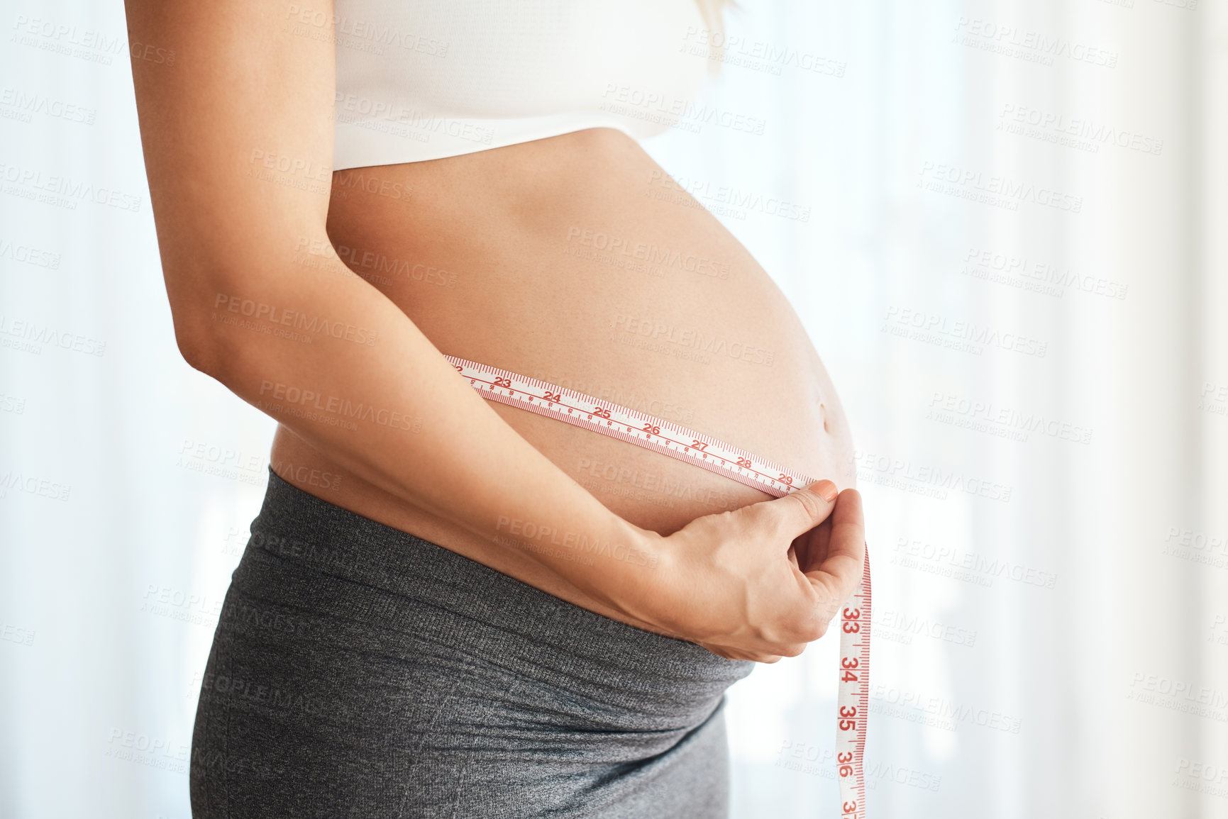 Buy stock photo Pregnant woman, hands and tape measure in home for tracking personal milestone, fetal growth and development. Person, closeup and monitor pregnancy belly for maternity care, wellness and progress.