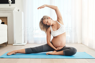 Buy stock photo Shot of a pregnant woman doing yoga on an exercise mat at home