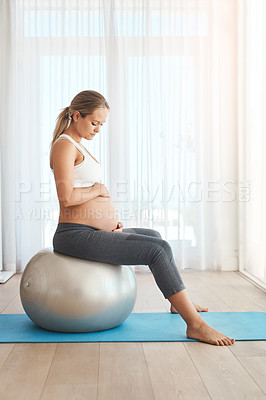 Buy stock photo Shot of a pregnant woman working out with an exercise ball at home