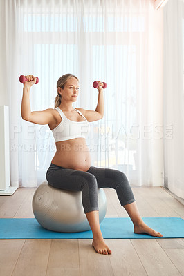 Buy stock photo Shot of a pregnant woman working out with an exercise ball and weights at home