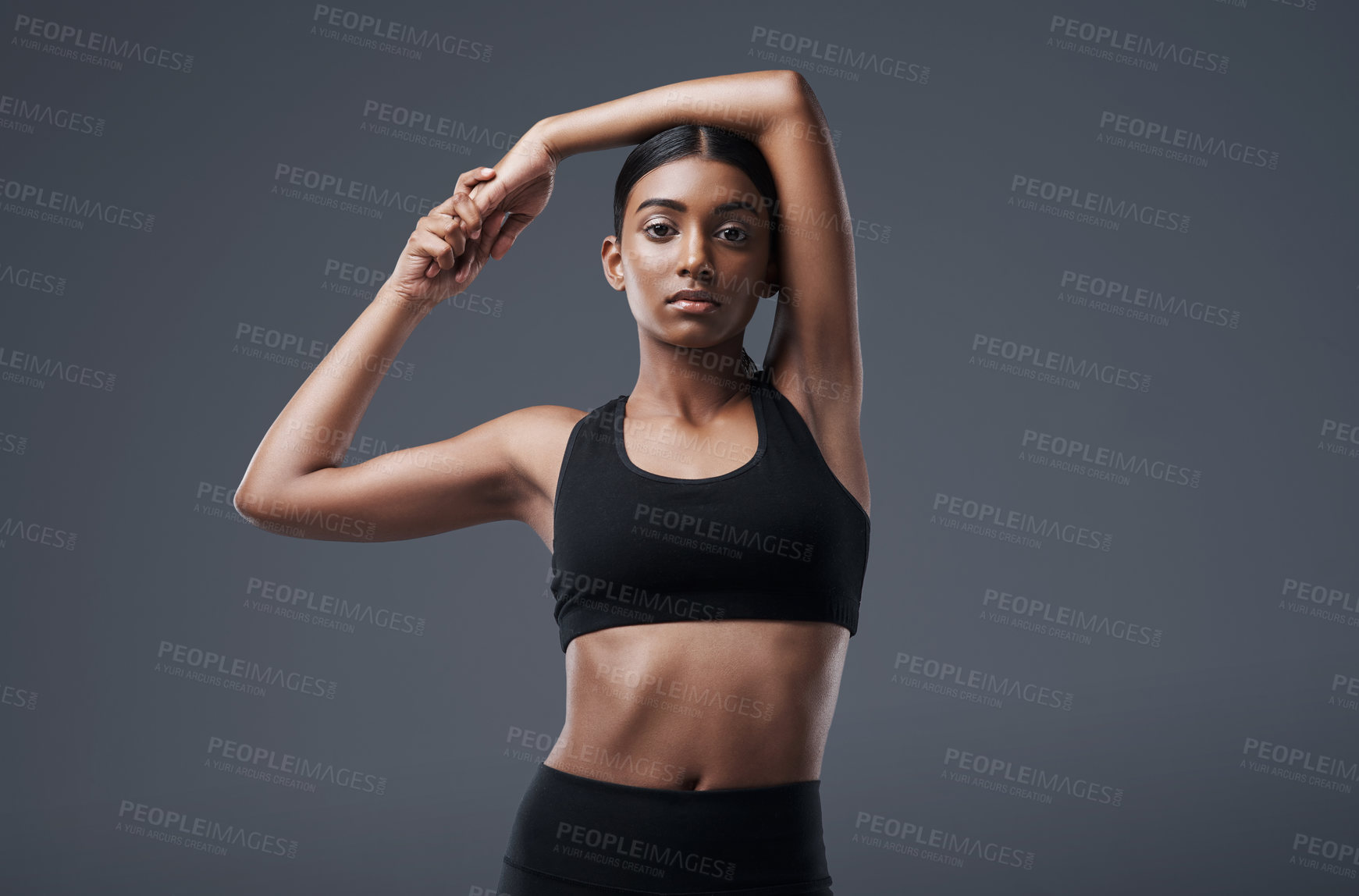 Buy stock photo Portrait, mockup space and stretching with a woman in studio on a gray background for exercise or health. Fitness, workout and warm up with an attractive young female athlete training her body