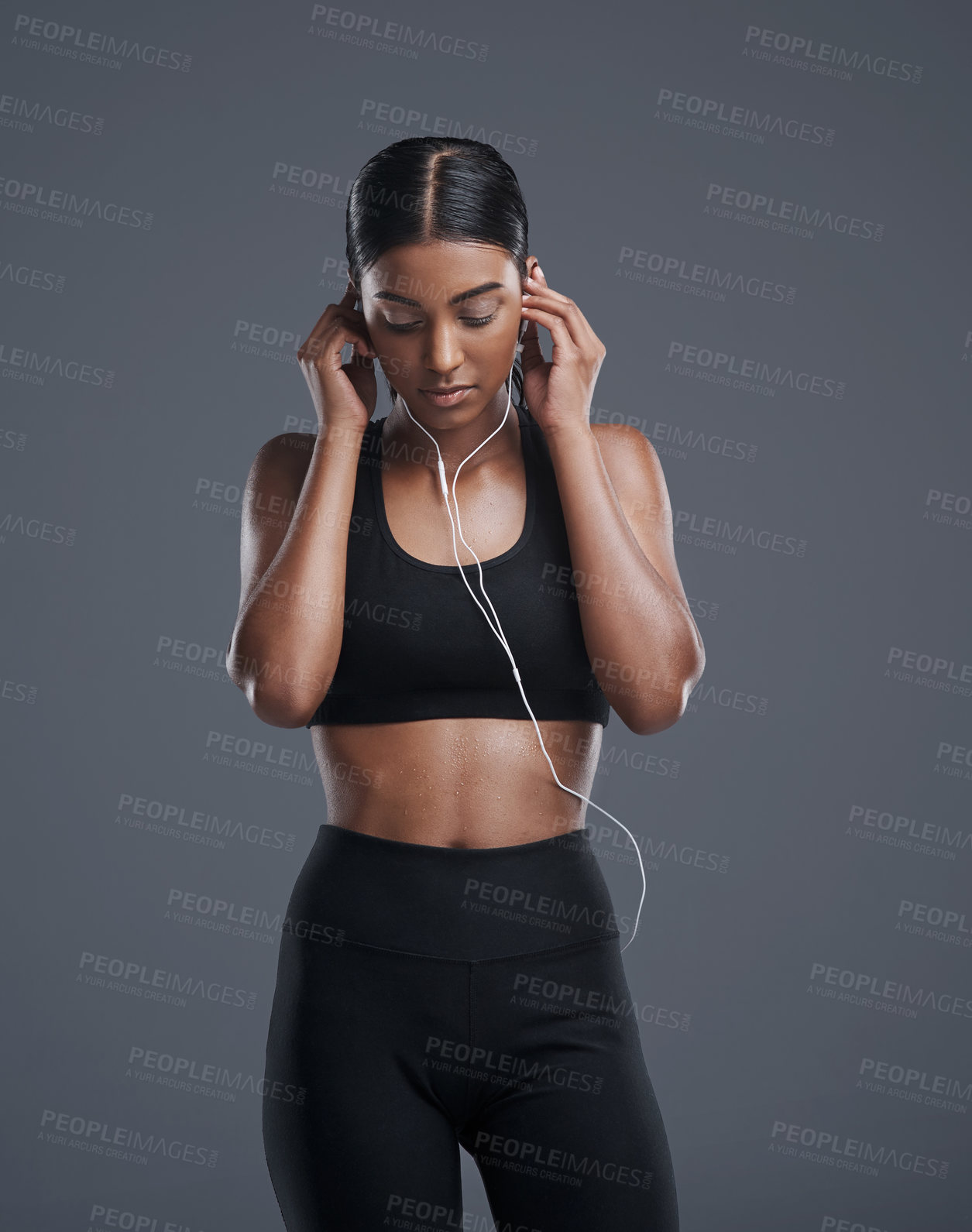 Buy stock photo Indian woman, music and earphones for workout in studio on grey background to exercise for health, fitness and committed. Female person, fashion and sportswear for gym or training and wellbeing
