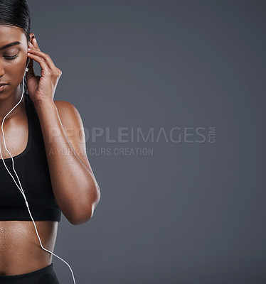 Buy stock photo Studio shot of a sporty young woman listening to music against a grey background
