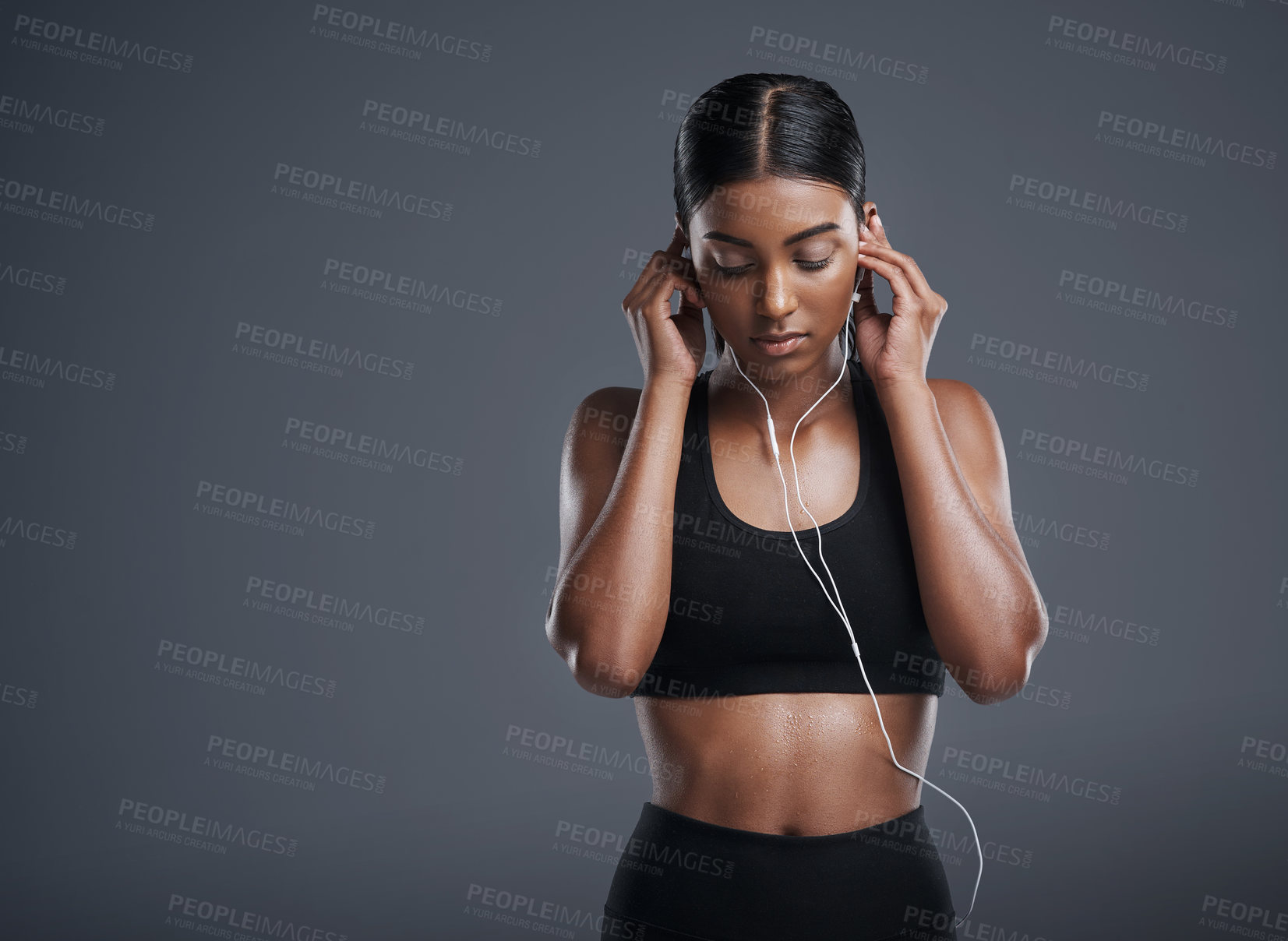 Buy stock photo Woman, fitness and headphones in studio for music, listening and podcast by dark background. Female athlete, streaming and audio for workout, sports training and thinking of playlist on mockup space