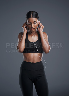 Buy stock photo Studio shot of a sporty young woman listening to music against a grey background