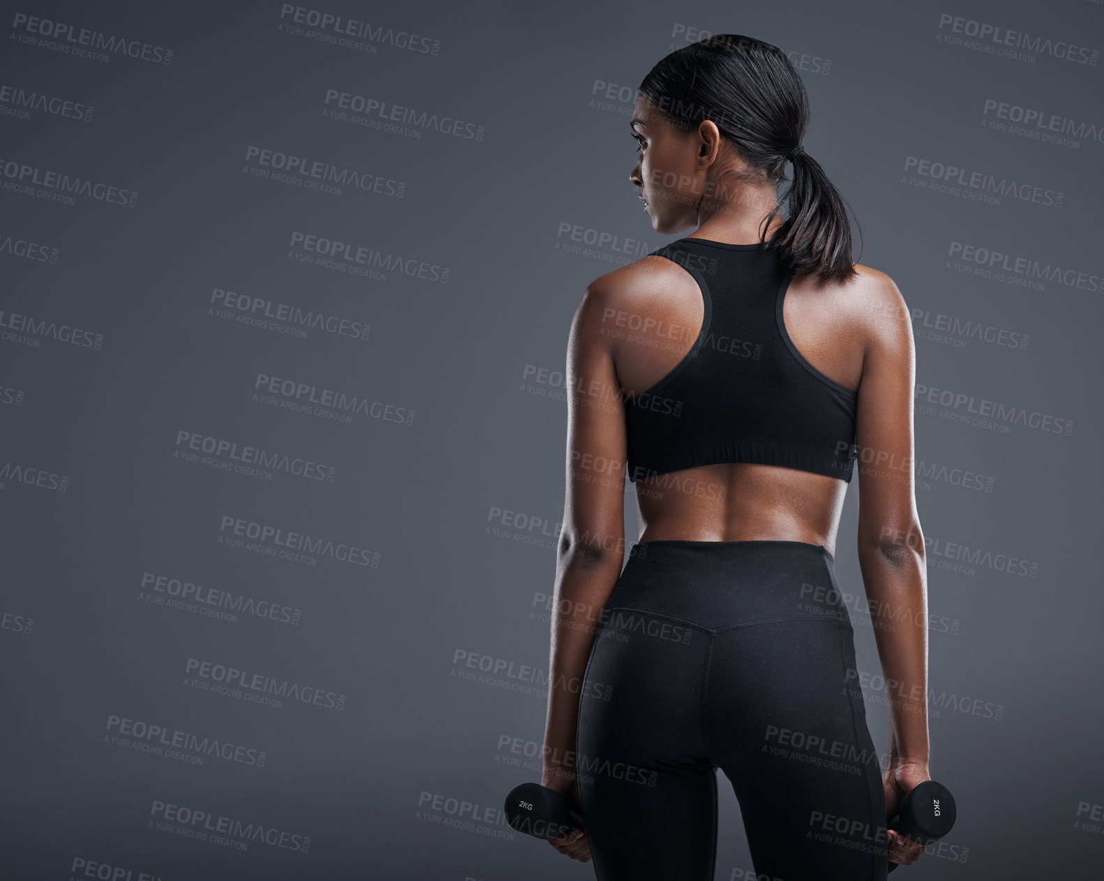 Buy stock photo Studio shot of a sporty young woman lifting weights against a grey background