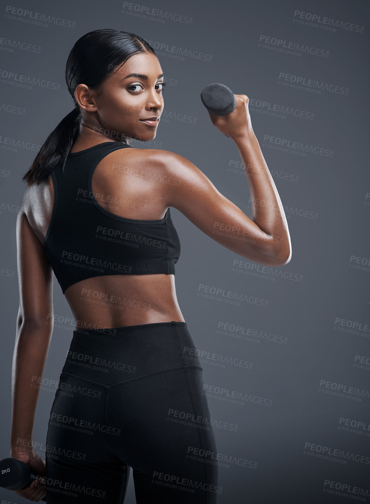 Buy stock photo Indian woman, dumbbells and workout or exercise in studio on grey background for health, muscles and fitness. Back view, sportswear and committed for wellbeing with weights for training and self care