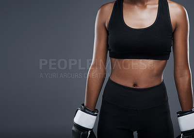 Buy stock photo Studio shot of a sporty young woman wearing boxing gloves against a grey background