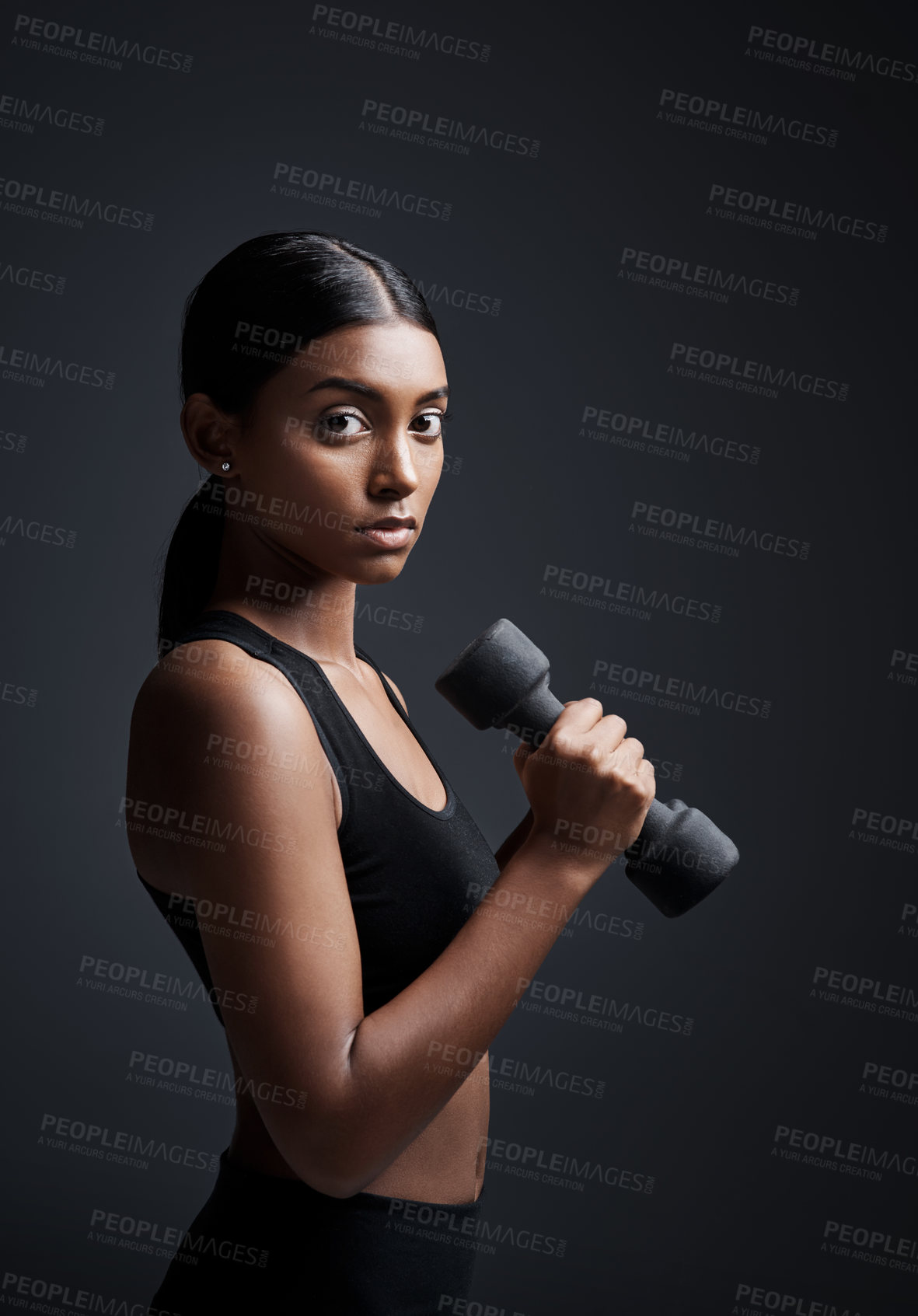 Buy stock photo Portrait, serious and woman with dumbbell for workout in studio isolated on a black background. Strong, bodybuilder and Indian female athlete weightlifting for muscle, training and fitness exercise.