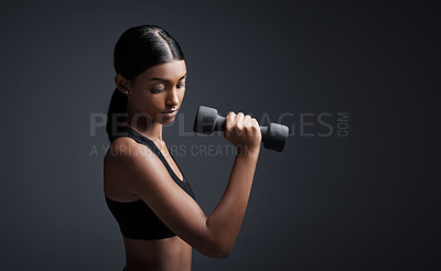 Buy stock photo Studio shot of a young sportswoman doing dumbbell exercises against a gray background