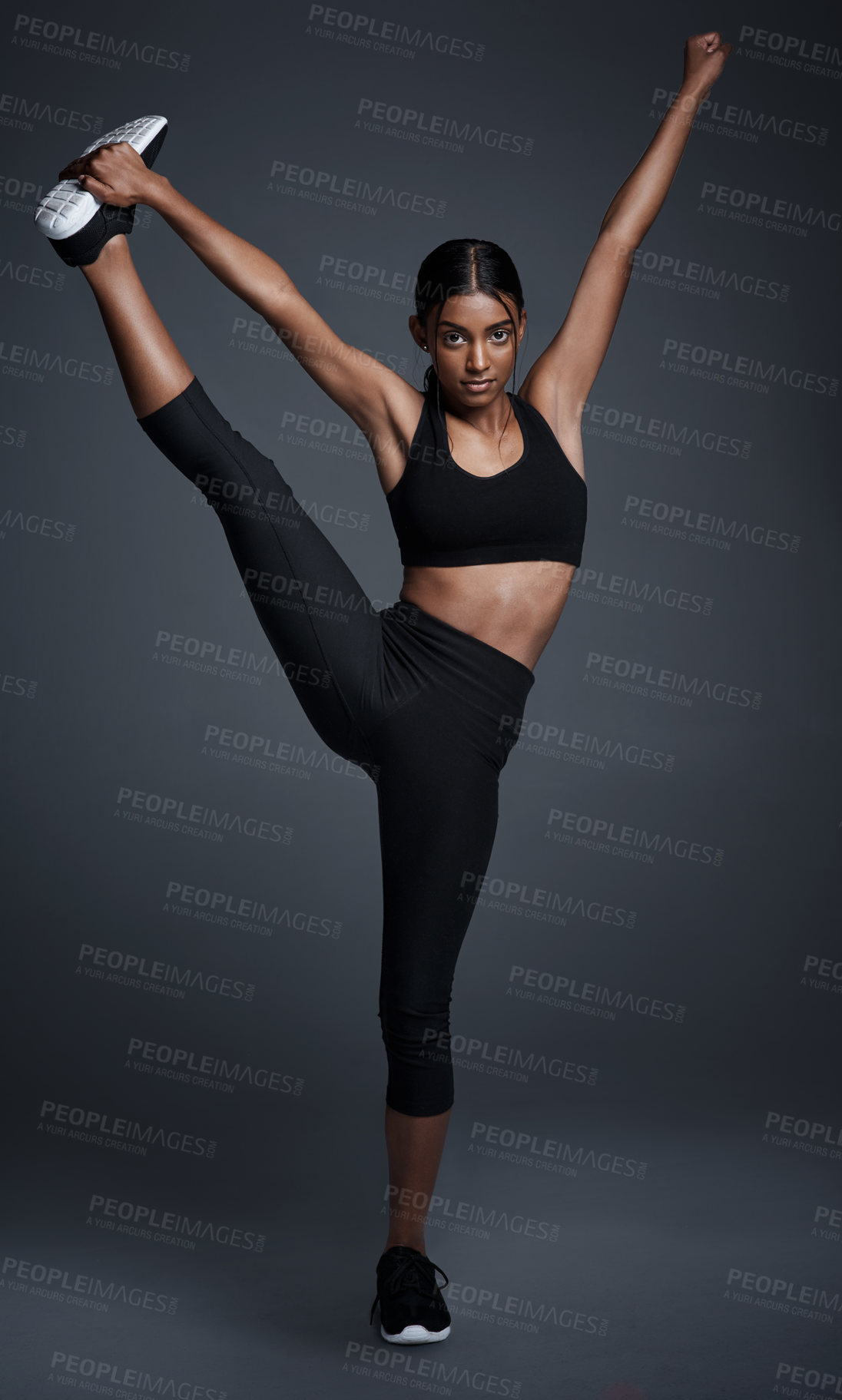 Buy stock photo Indian woman, portrait and leg stretching or flexible challenge in studio for mobility, pilates or mockup space. Female person, face and warm up for balance workout or yoga, black background or goals