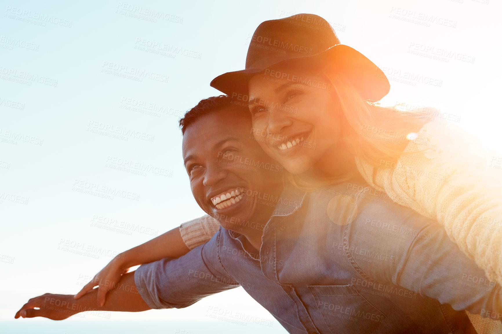 Buy stock photo Shot of a happy young couple enjoying a piggyback ride outdoors