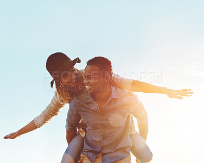 Buy stock photo Shot of a happy young couple enjoying a piggyback ride outdoors