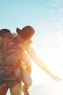 Buy stock photo Shot of a happy young couple enjoying a piggyback ride outdoors