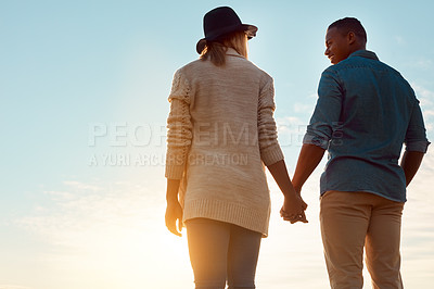 Buy stock photo Rearview shot of a happy young couple holding hands outdoors