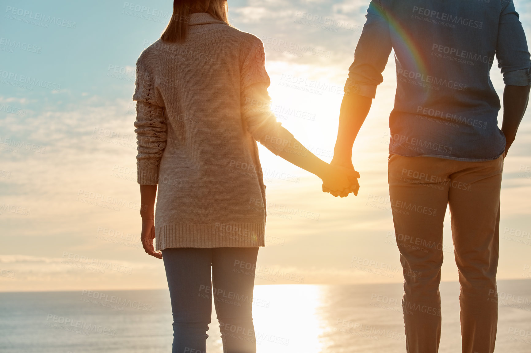 Buy stock photo Rearview shot of a young couple holding hands and overlooking an ocean view