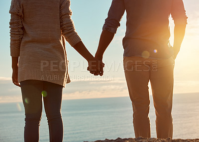Buy stock photo Rearview shot of a young couple holding hands and overlooking an ocean view