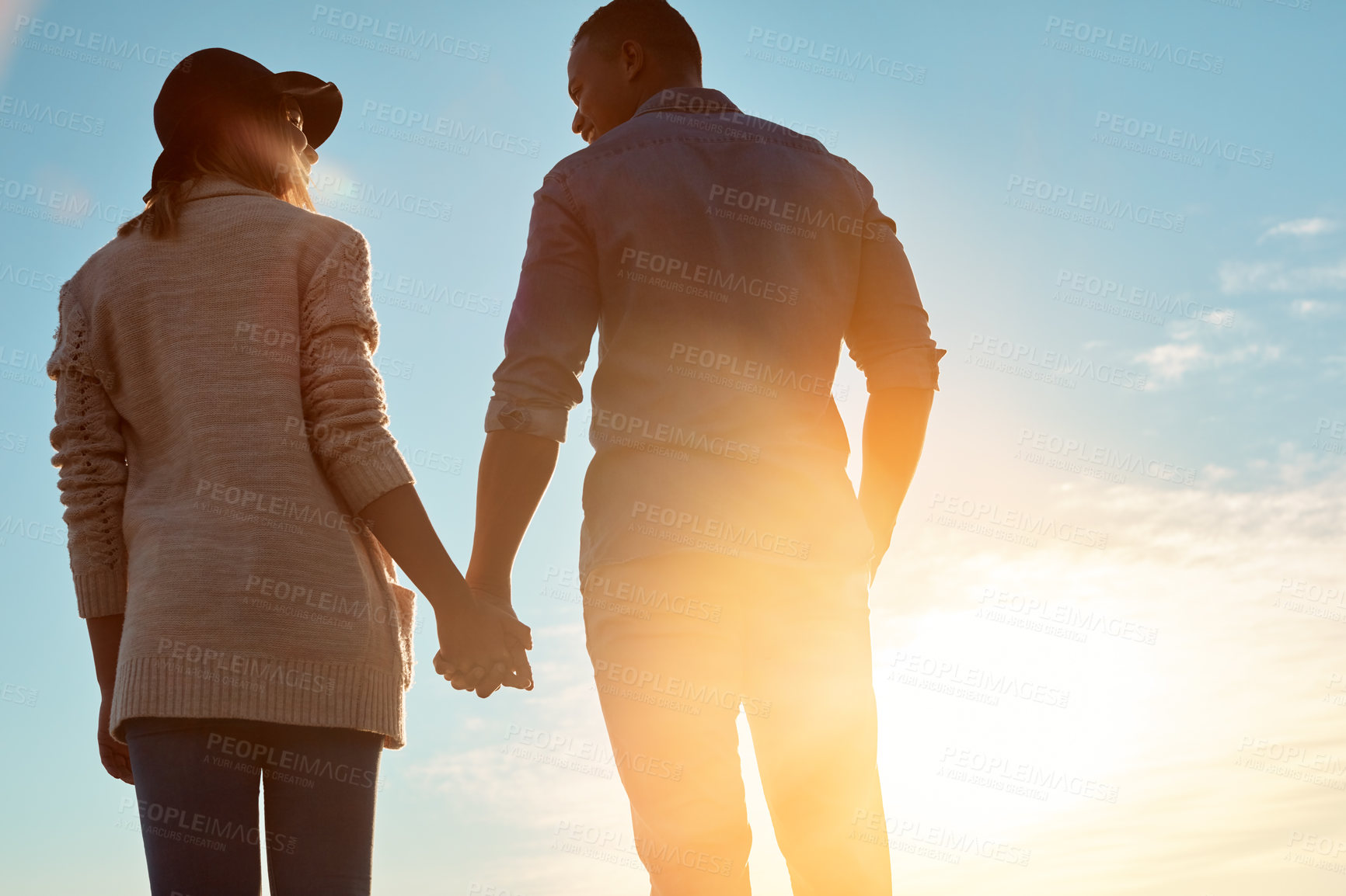 Buy stock photo Rearview shot of a happy young couple holding hands outdoors