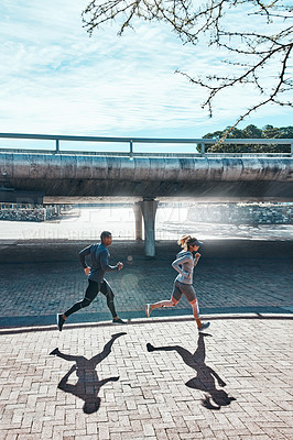 Buy stock photo Full length shot of two young and athletic young people running through the city