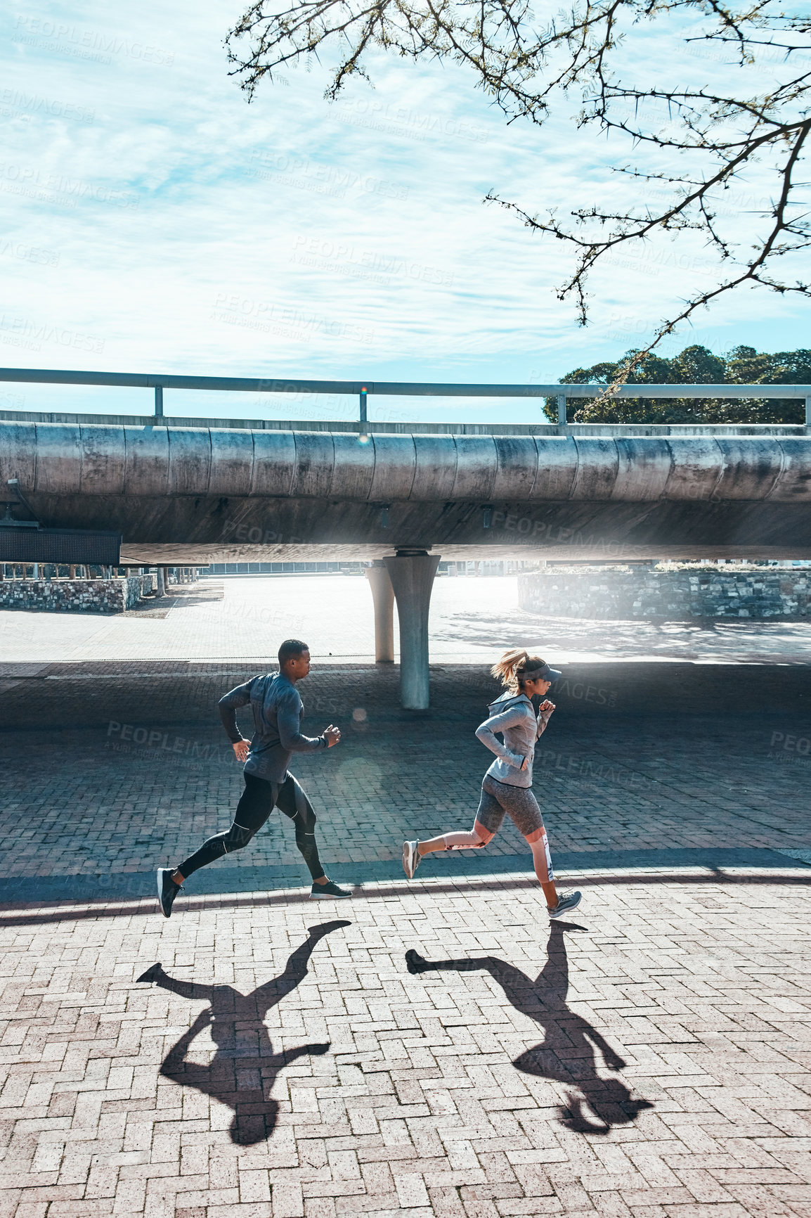 Buy stock photo Full length shot of two young and athletic young people running through the city
