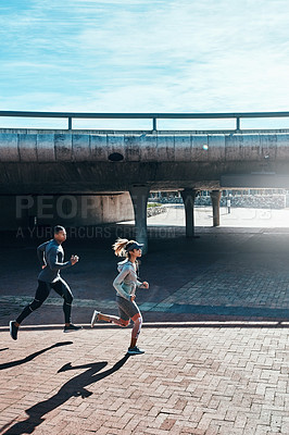 Buy stock photo Full length shot of two young and athletic young people running through the city