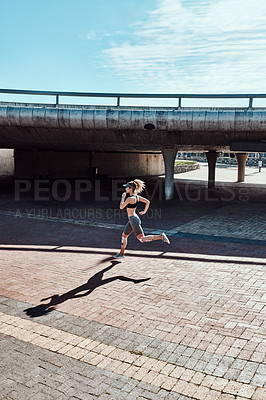 Buy stock photo Full length shot of an attractive and athletic young woman running through the city